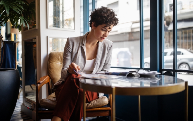 Woman sitting at table reading magazine